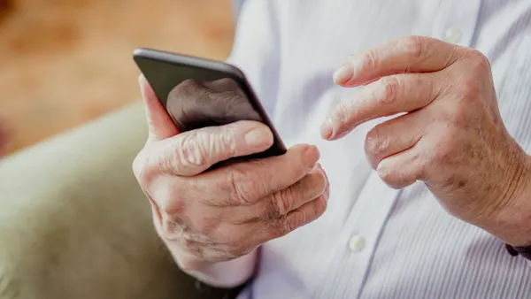 A close-up shot of an older person holding a mobile phone.