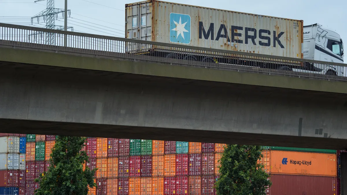 A lorry is driving over a bridge where underneath shipping containers stand stacked at Hamburg Port.