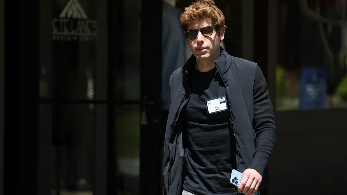 Sam Altman, CEO of OpenAI, walks casually outside in the sun.