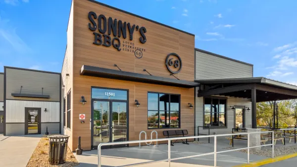 A daytime photo of a light brown building. It has a black sign that says "Sonny's BBQ Local Pitmasters Since '68"
