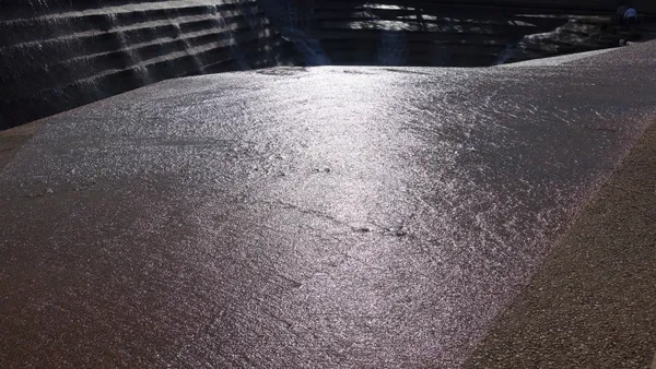 An engineered fountain spills shallow water over a concrete basin.