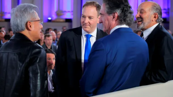 Four men stand in a group talking.