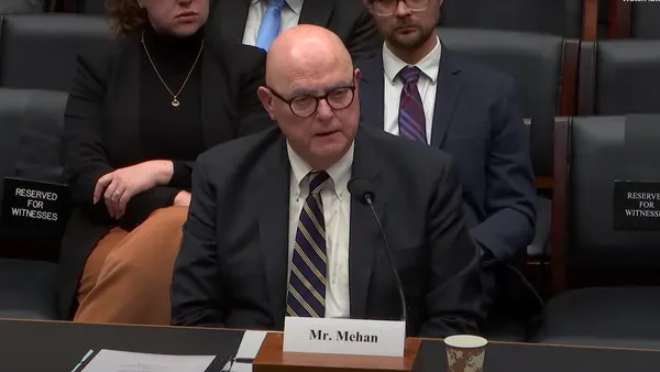 A man sits at a desk with a microphone