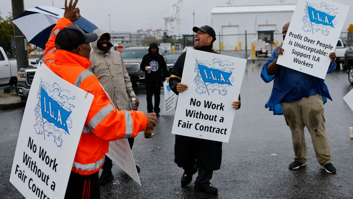 Dockworkers hold picket sign, striking at a port in Baltimore.