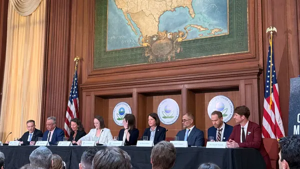 A line of speakers sit side by side underneath a decorative map