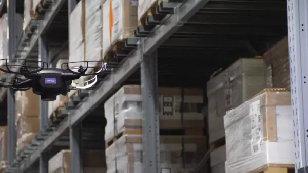 A Verity-manufactured drone hovers nearby boxed inventory in a warehouse.