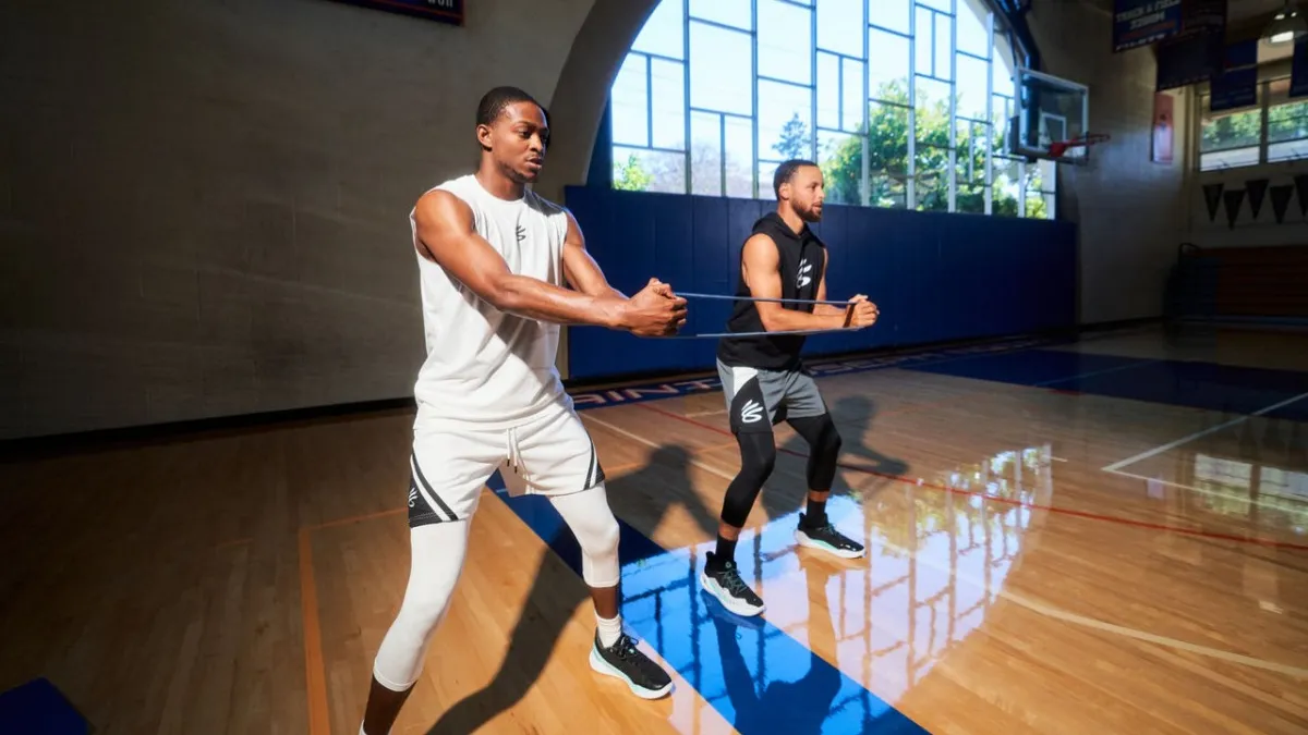 De'Aaron Fox and Steph Curry work out in a gymnasium.