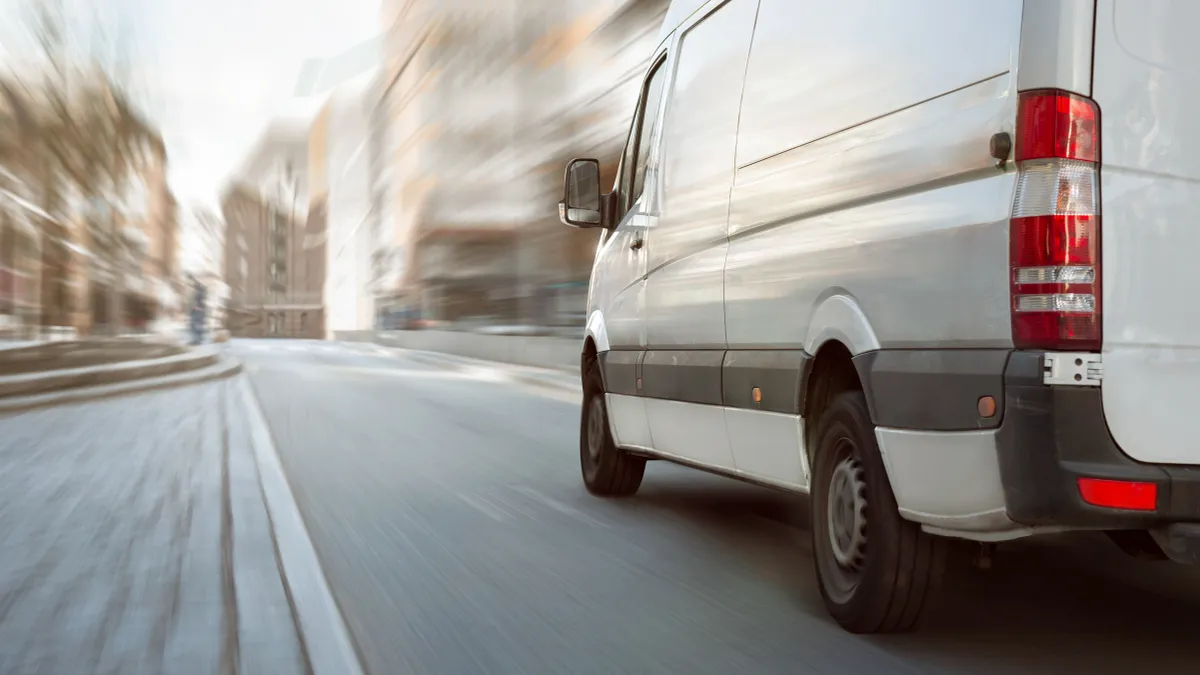 White transporter driving inside the city