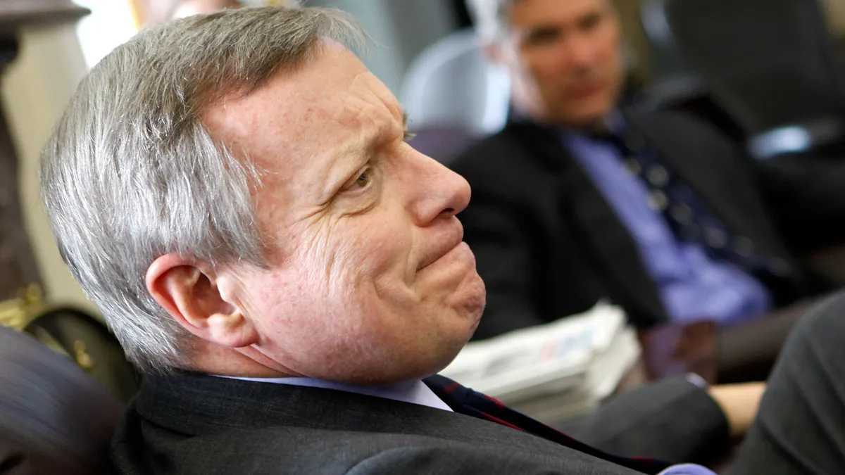 Sen. Dick Durbin with his hand up and another congressional colleague in the background.