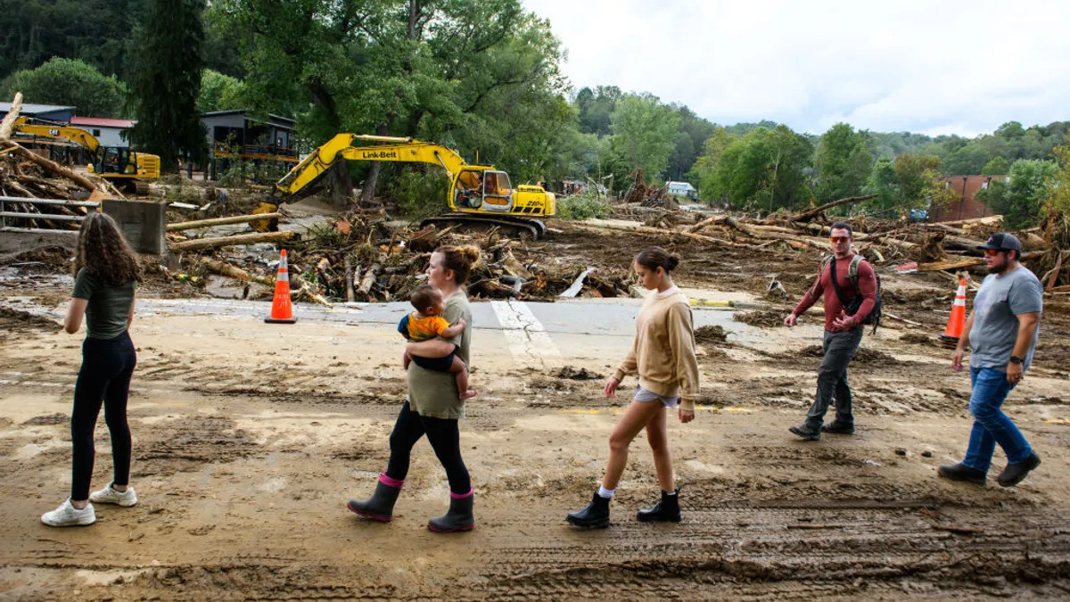 Residents walk along Catawba Avenue while debris is cleared in the aftermath of Hurricane Helene on Sept. 29 in Old Fort, North Carolina.