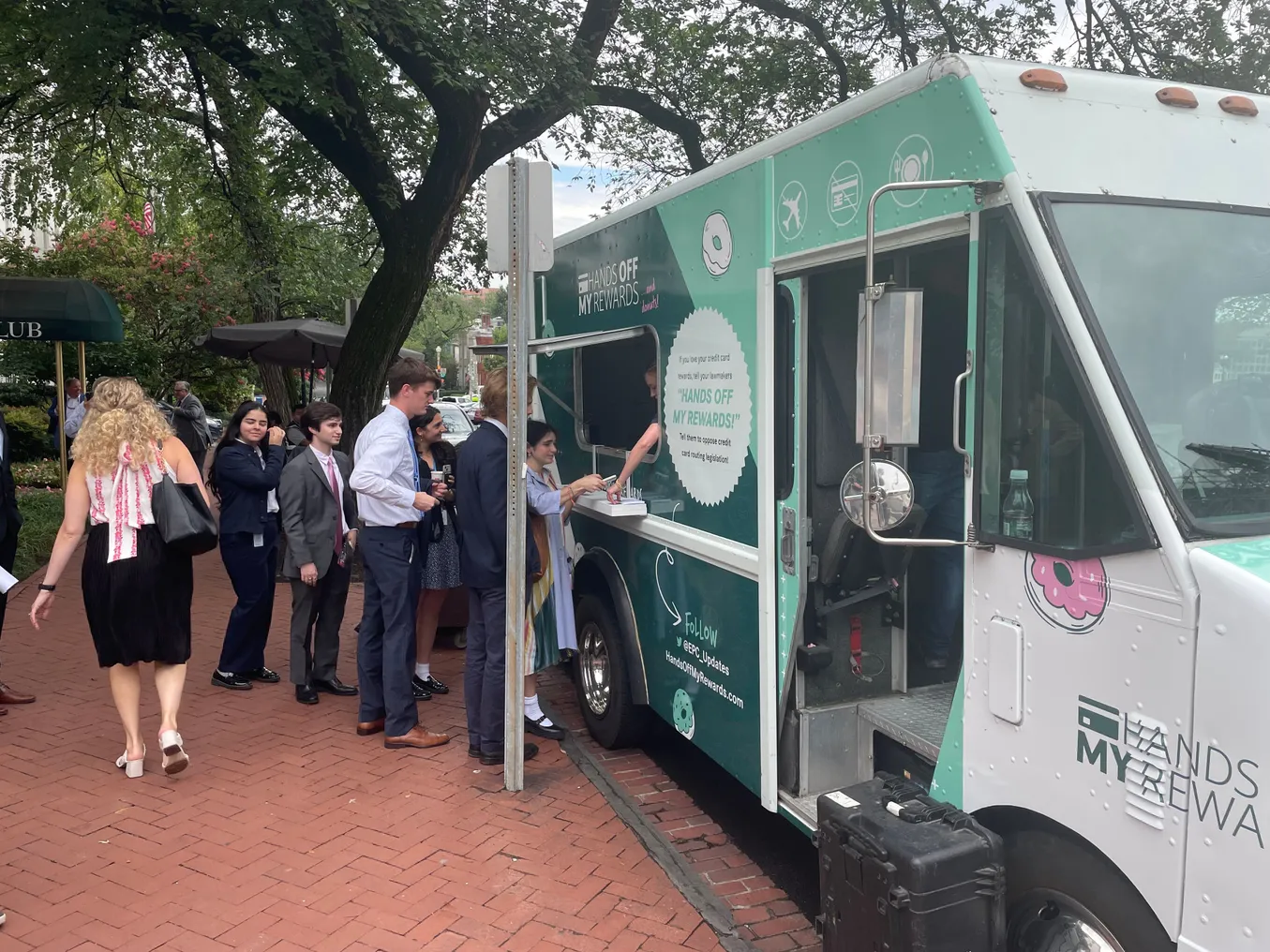 People walk around in front of a truck offering free donuts.