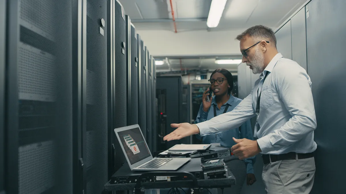 Shot of a man and woman looking stressed while working in a data centre