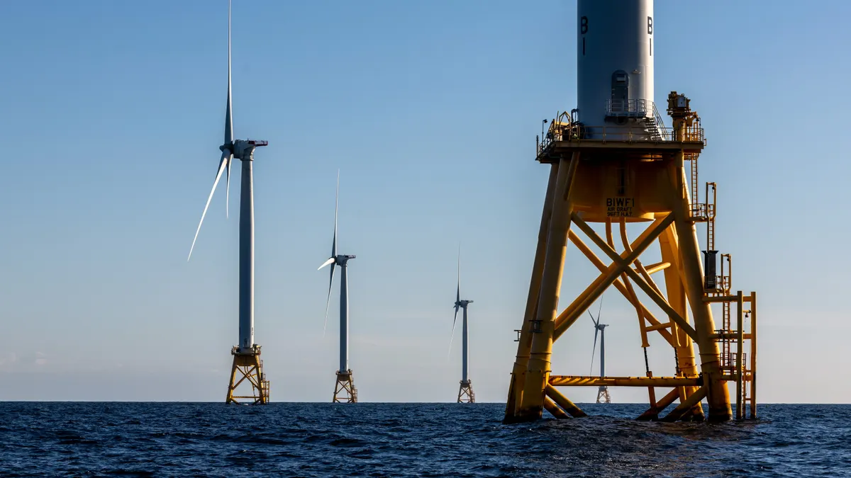 Offshore wind farm turbines spin over the ocean.