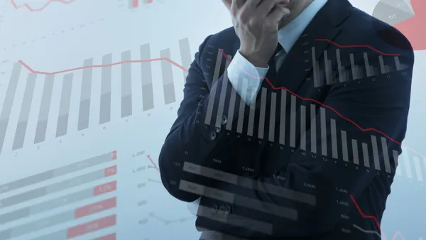 Businessperson feeling anxiety and stress amid graphics of declining graphs and charts.