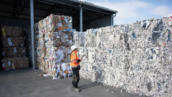 A person in a hard hat inspects a bale of recyclables