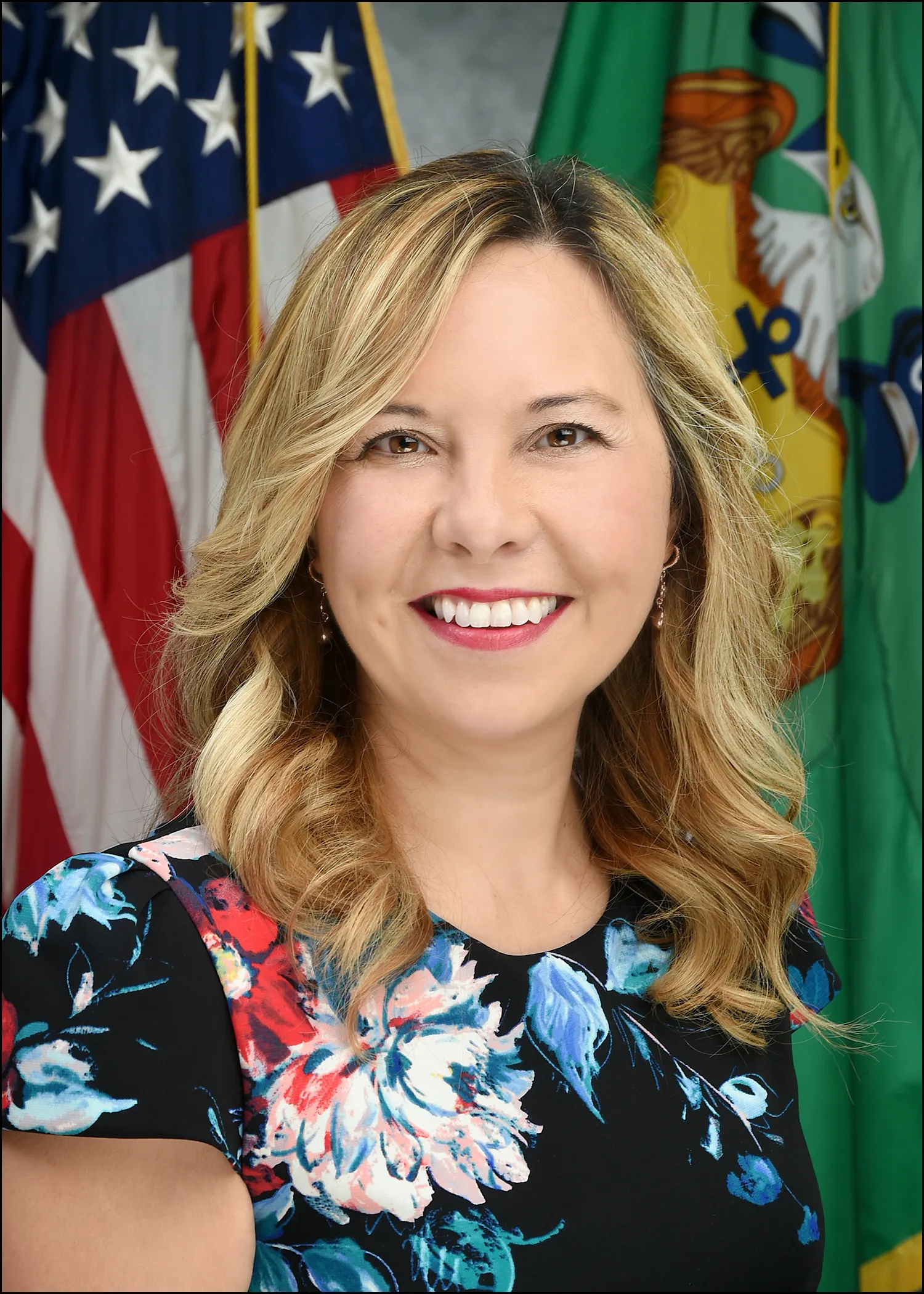 Christy Goldsmith Romero poses for a photo in front of flags