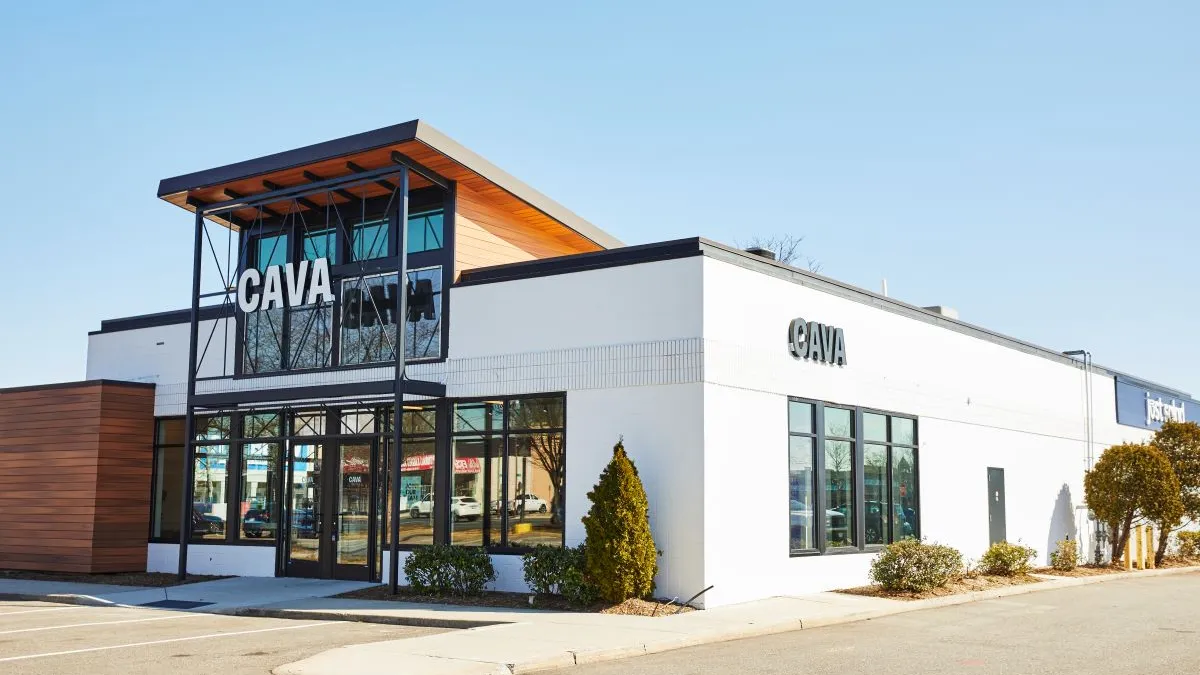 A white building with windows on the front with a large sign that says Cava