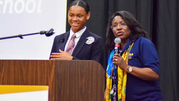 Topeka Public Schools student Simone Holloway stands onstage with Superintendent Tiffany Anderson at a school district event.