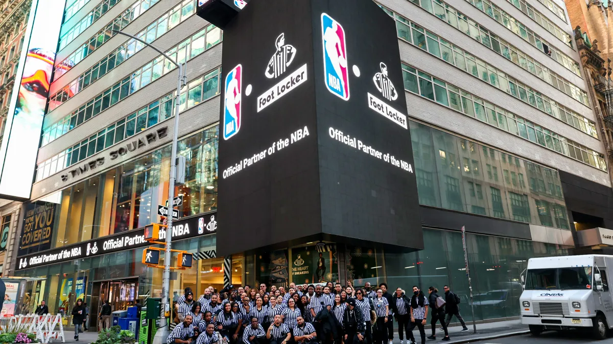 Employees outside of the Times Square Foot Locker store. A Foot Locker and NBA sign hangs overhead.