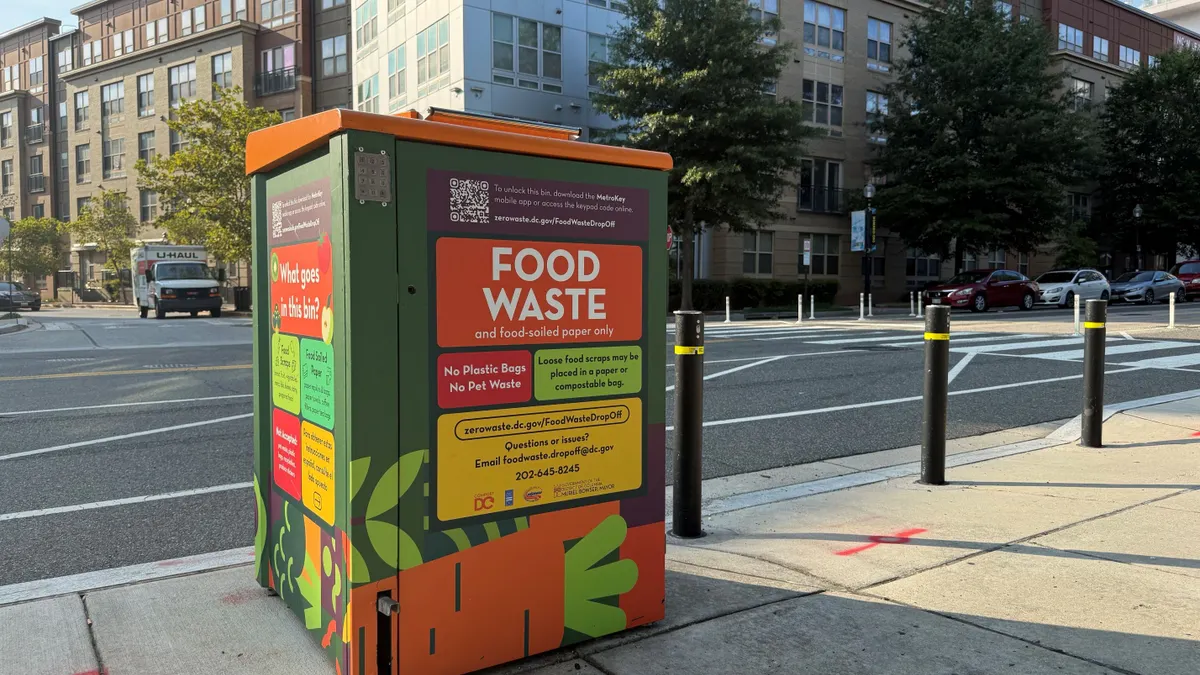 An automated metal food waste bin sits on the side of the road