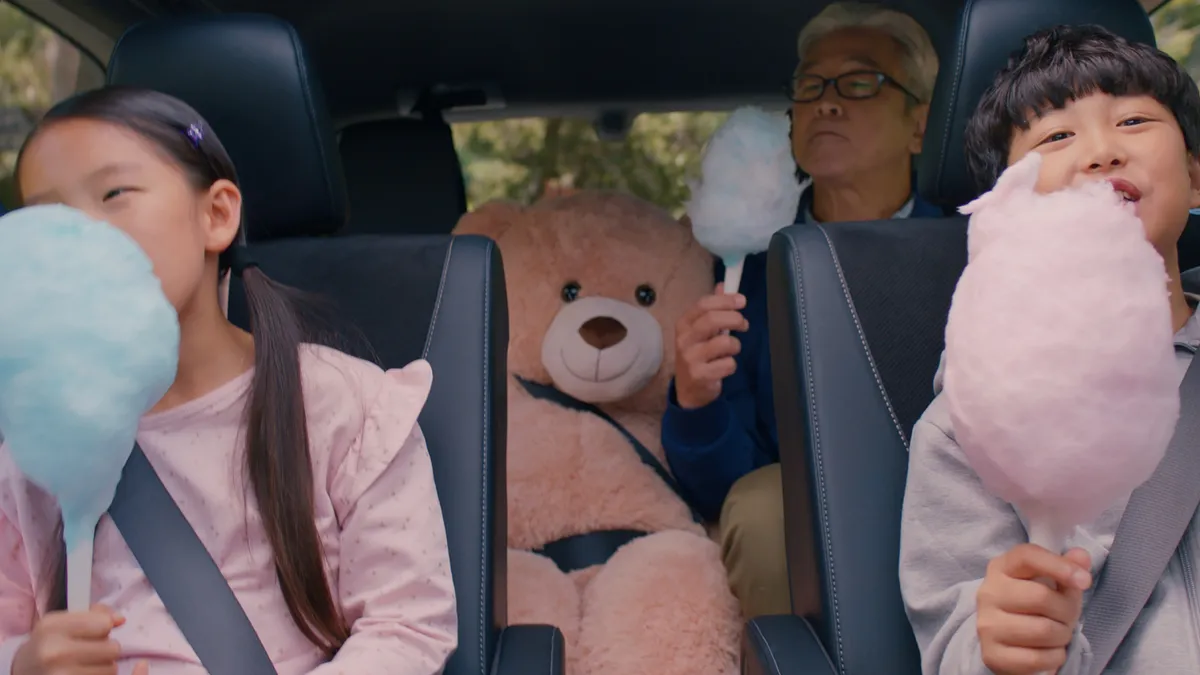 Two kids sit in the middle row while their grandfather sits in the back row of a Grand Highlander in an ad for Toyota.