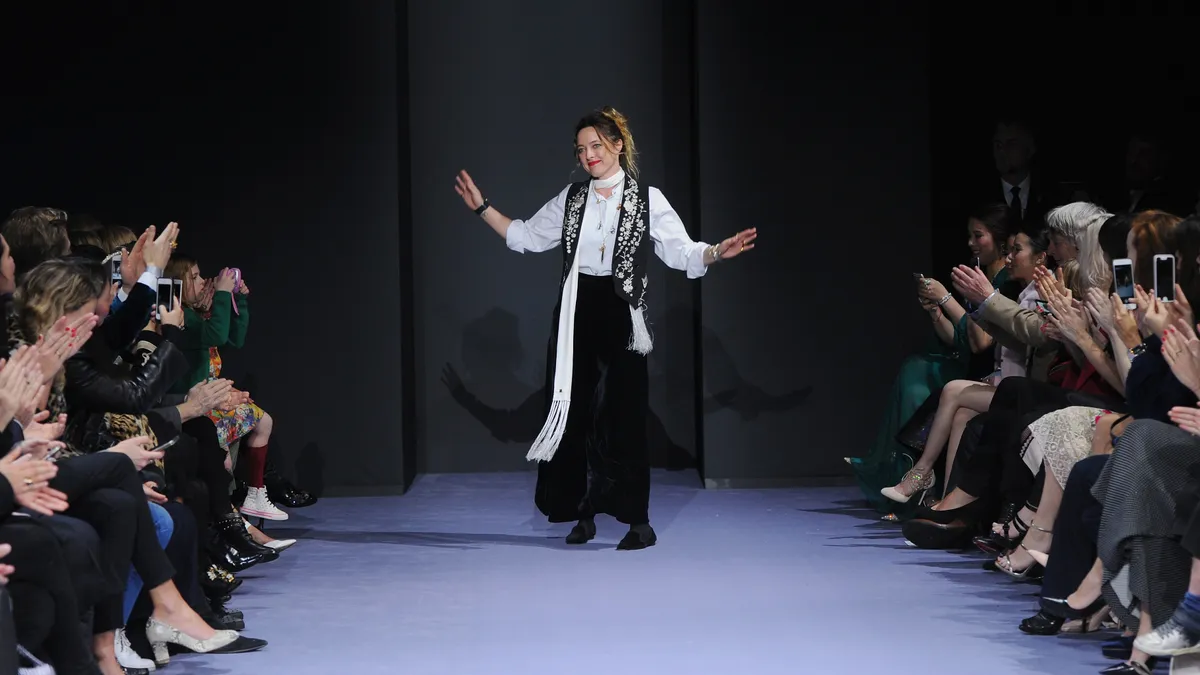 Alice Temperley, of Temperley London, walks on a runway and is met with applause.