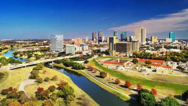 Aerial of Fort Worth during autumn with the Trinity River and riverbank parks in the foreground as well as city skyline in the background.