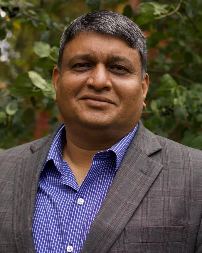 A head and shoulders photo of a person against a background of leaves.