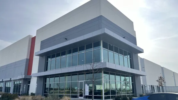 The corner of a gray and beige glass building.