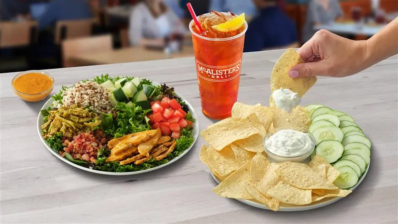 An image of a plate of greens and grains and another plate of hummus and vegetables.