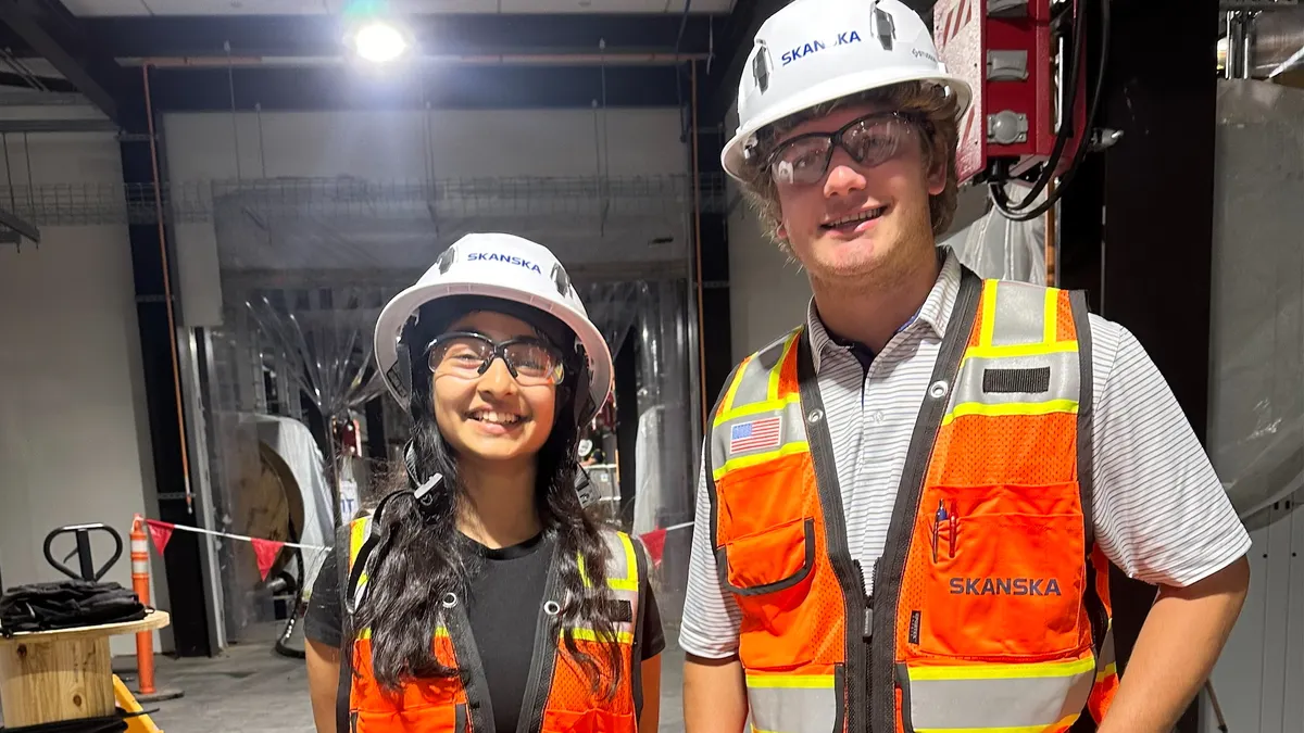 Two construction interns stand side by side on a jobsite