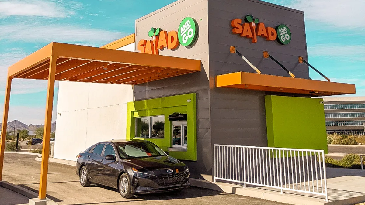 A car at a window picking up an order from a restaurant