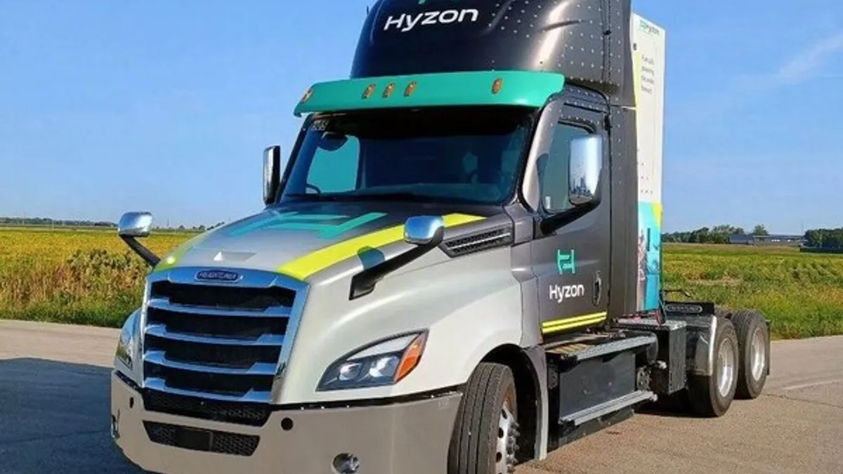 A Hyzon fuel cell electric truck in front of a grassy field.