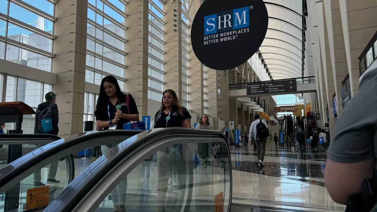 Individuals walk through a conference hall below a SHRM sign.