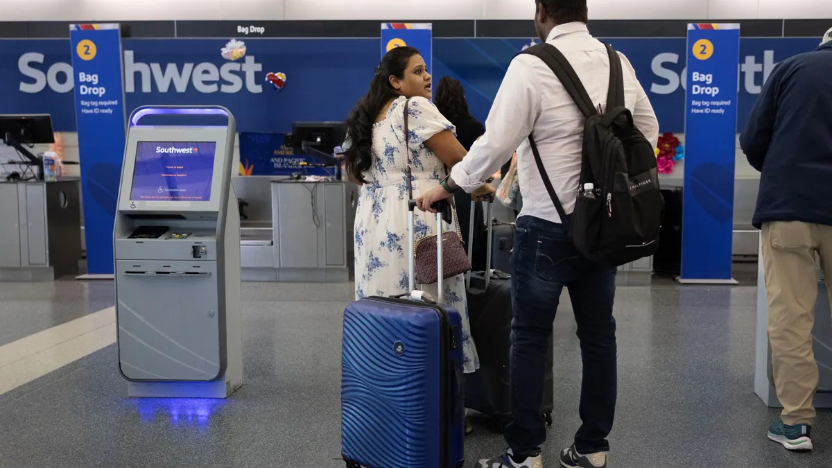 People wait in line to check in for flights with their luggage.