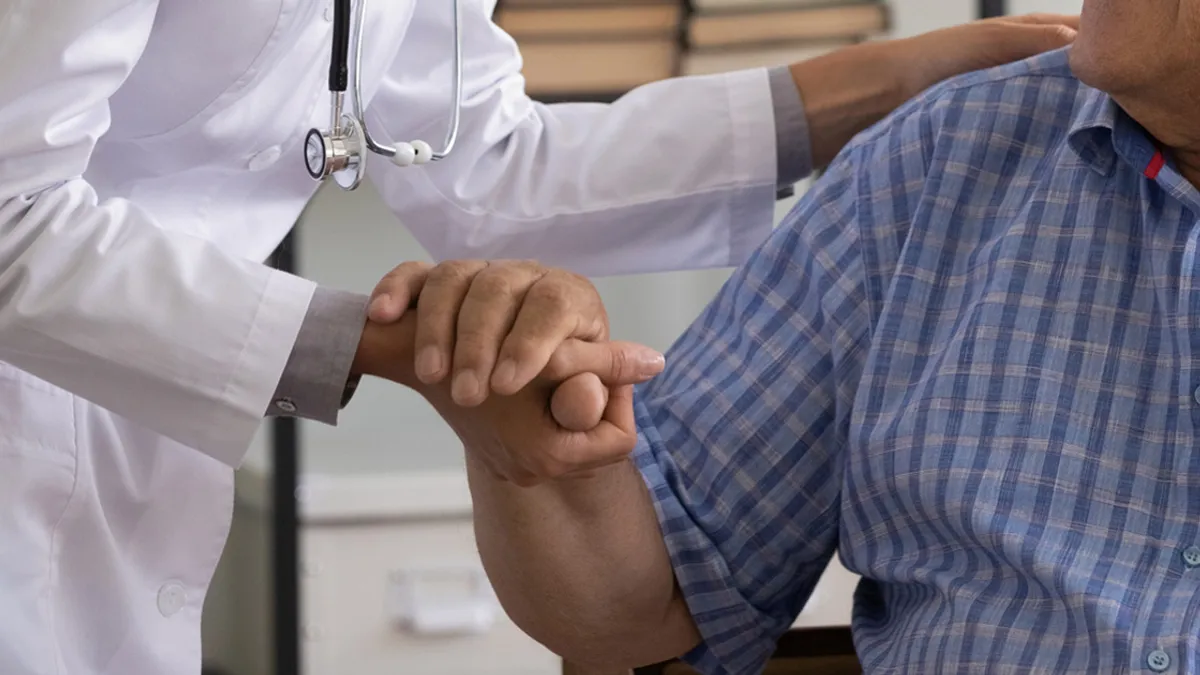 Thankful mature sick man holding nurse hand appreciating for help