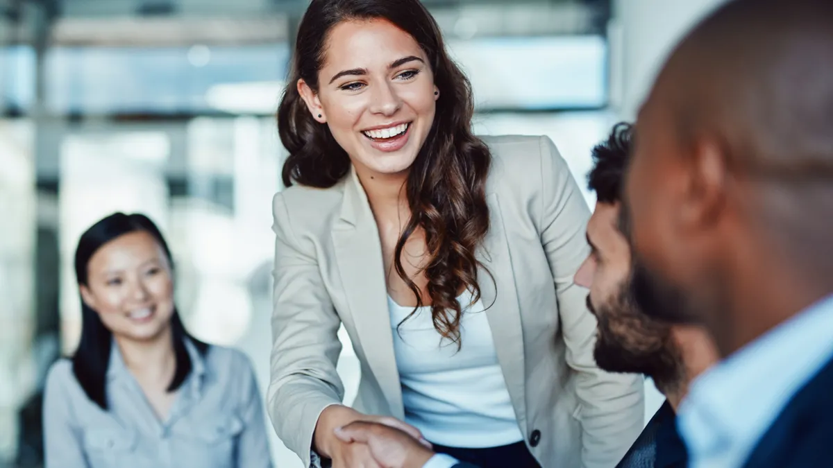 A female employee shaking another employee's hand