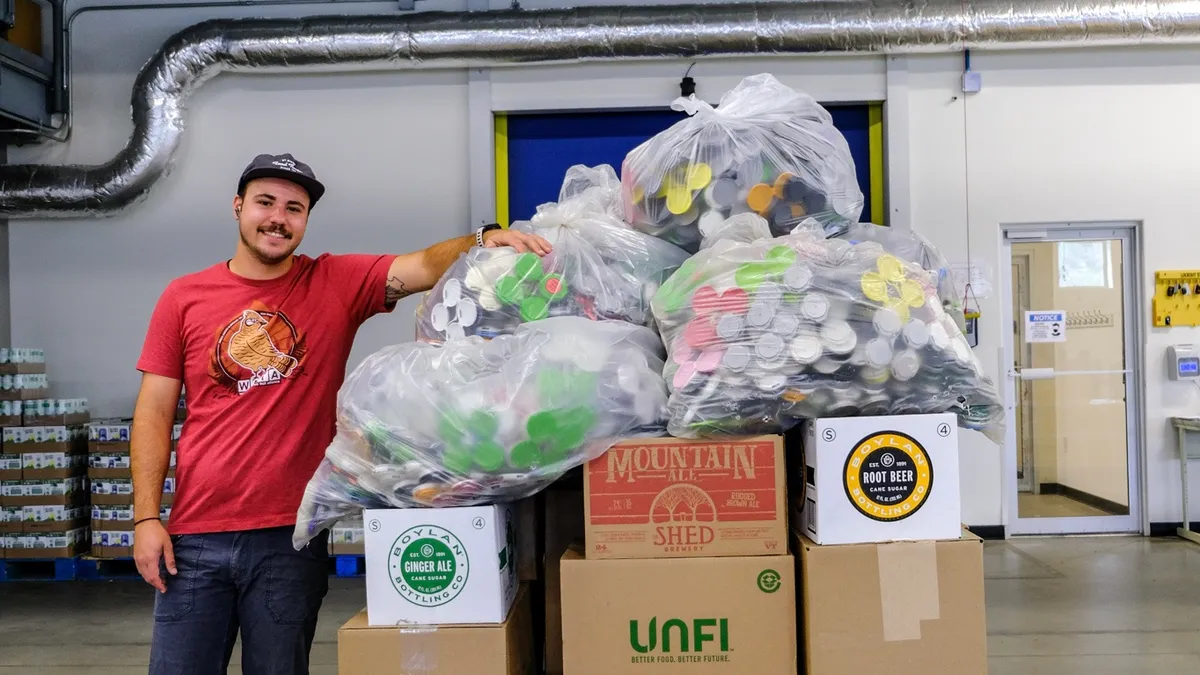 Person standing next to a pallet full of plastic beer can carriers