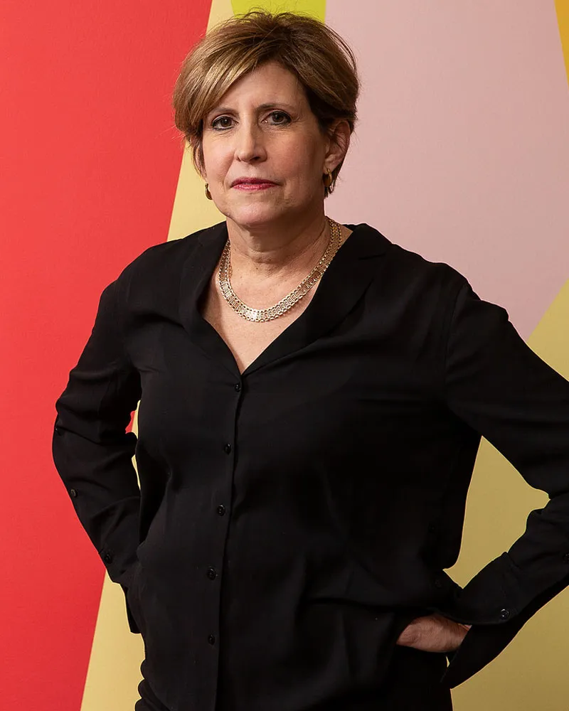 A person standing in front of an abstract background of red, pink and yellow.