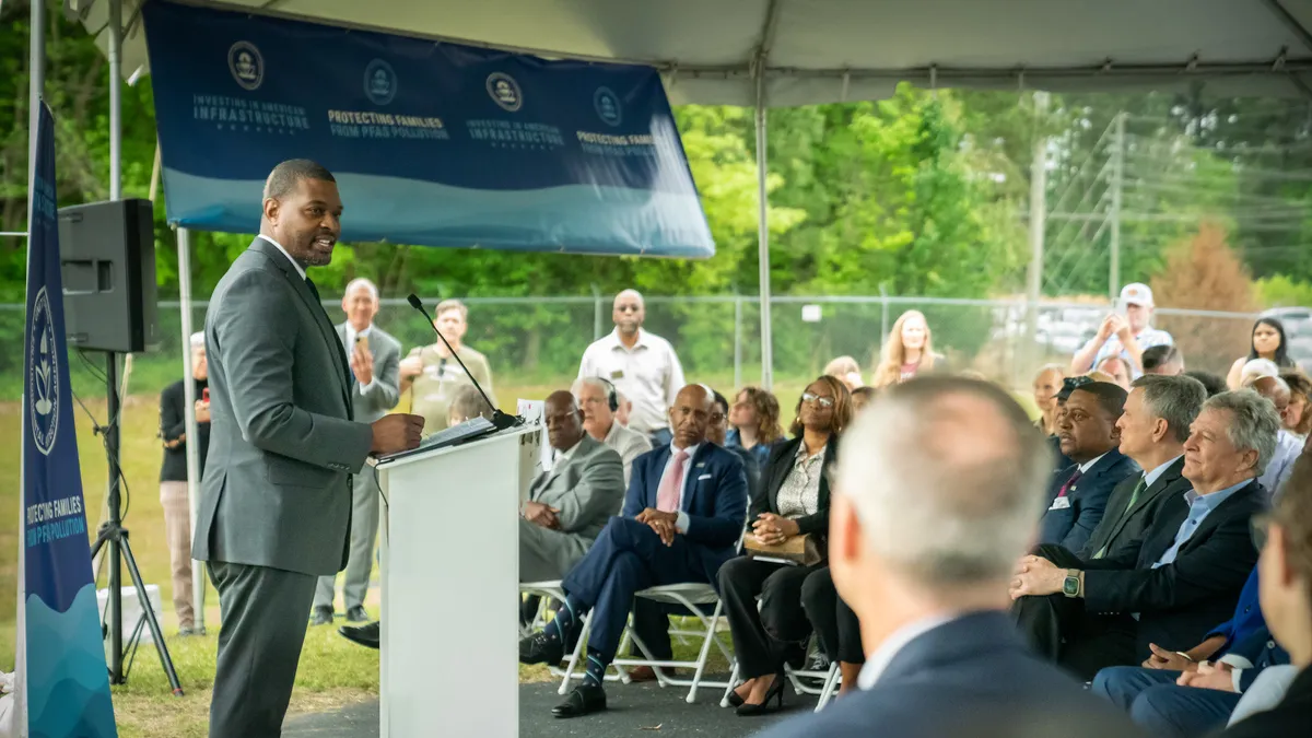 EPA Administrator Michael Regan speaks at a PFAS regulation event in front of a crowd of people under a tent