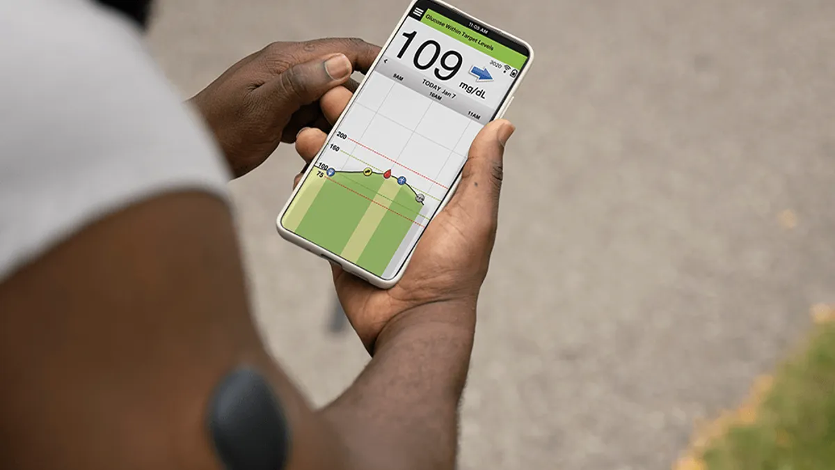 A picture of a man looking at a diabetes tracking app on his phone.