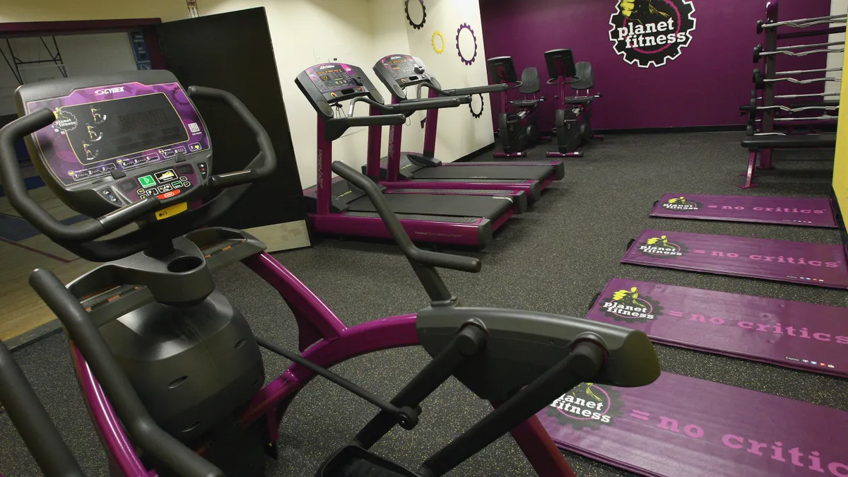 Several exercise machines in a room with a Planet Fitness logo.