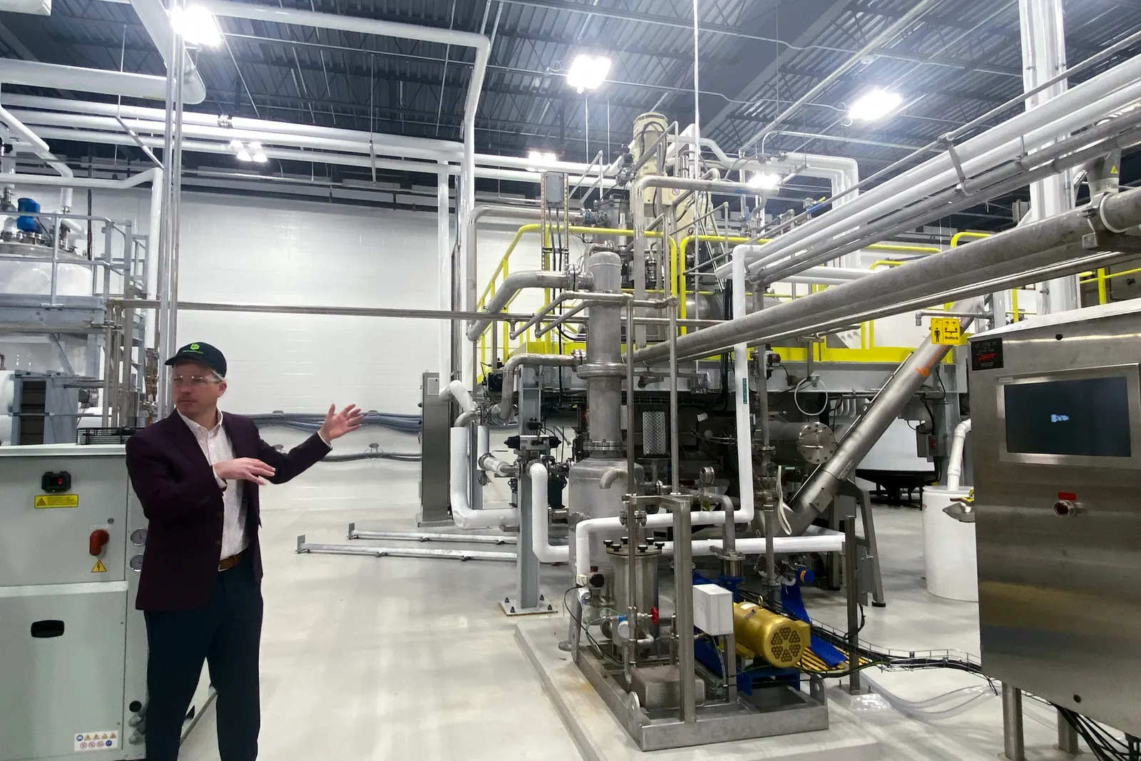 A man stands to the left of a large piece of machinery in a facility.