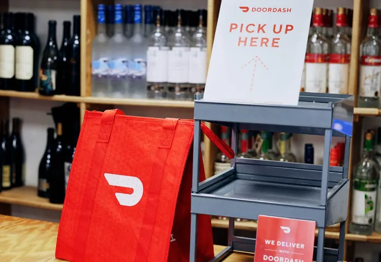 A delivery bag in front of bottles of alcohol in a store.