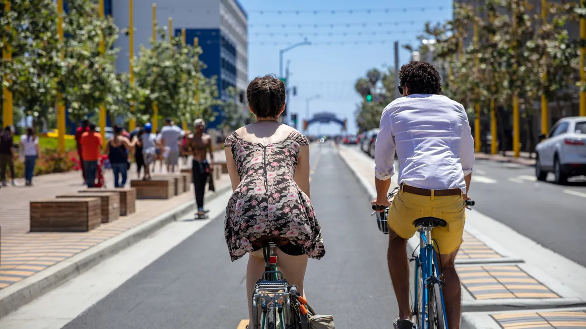 A man and woman are seen from riding bikes along a protected bike lane in Santa Monica, California.