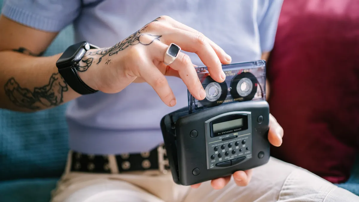 Tattooed person listening to cassette tapes with Walkman