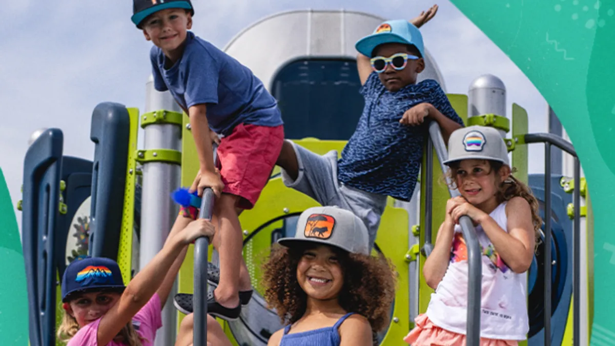 Five children, all wearing hats, climb on a jungle gym.