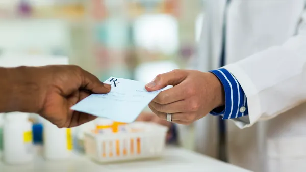 A man handing a prescription to a pharmacists