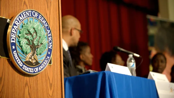 The Education Department's seal can be seen on a podium.