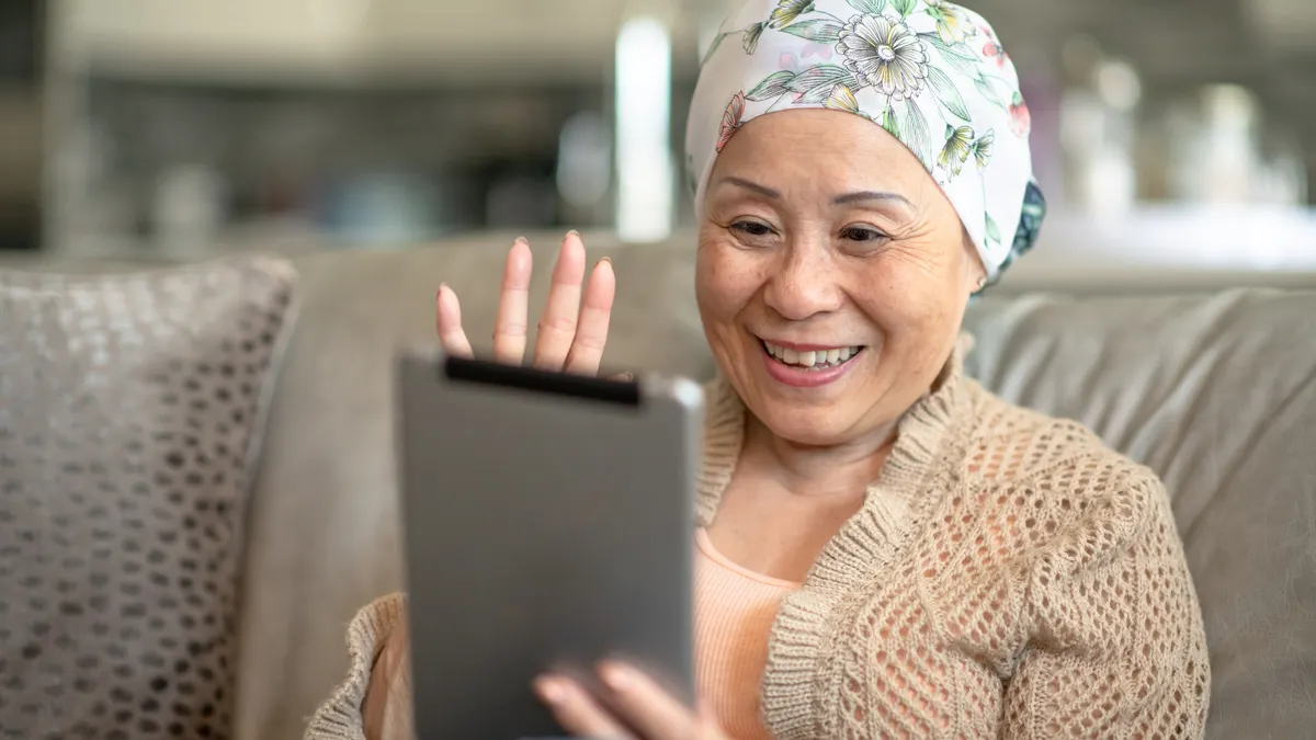 A woman smiles while interacting with someone on her digital tablet